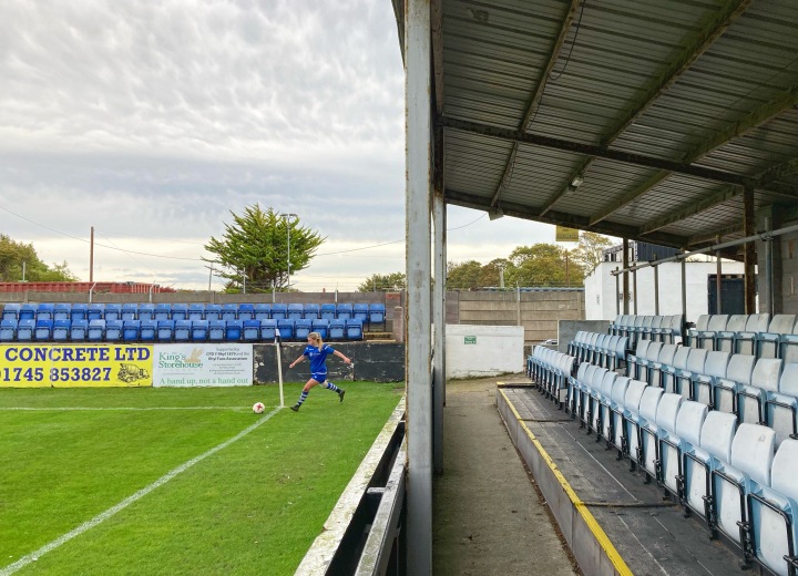 A player for NFA women takes a corner kick in front of empty stands at Belle Vue, Rhyl