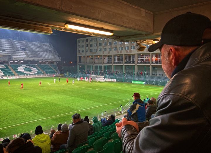 A man in a hat watches on as Gyor play DVTK at a very empty ETO Park stadium