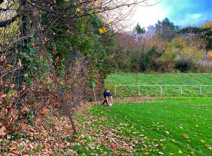 A Llandundo Junction player places the ball for a corner kick among autumn leaves