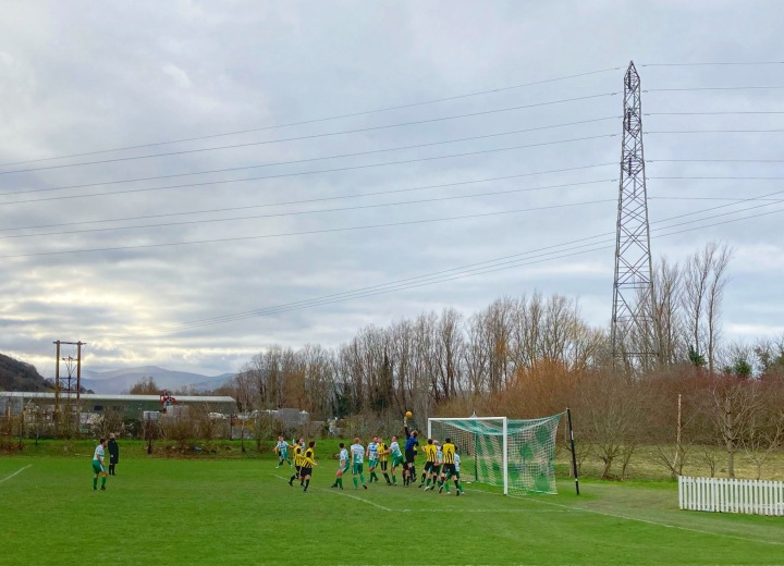 Match action from Mochdre Sports verus St Asaph City in front of a large pylon