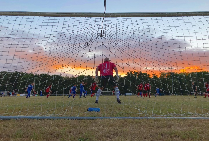 Newport Civil Service's goalkeeper faces a shot against Croesyceiliog as the sun sets on the latter's ground