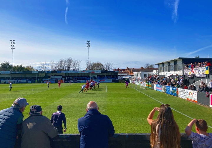Fans shield their eyes from the sun to watch Rhyl 1879 take a free-kick against Denbigh Town