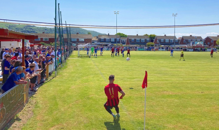 A Cefn Albion player takes a corner as Bangor 1876 supporters watch on at Prestatyn Town's Bastion Gardens
