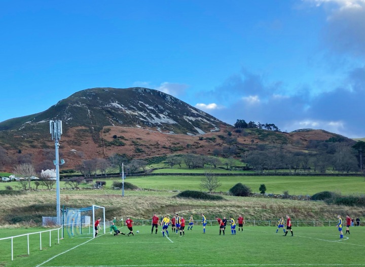 Match action from Penmaenmawr Phoenix against Llanfairfechan Town in front of a mountain